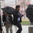 Varias personas sujetan sus paraguas intentando que no se les vuele debido al fuerte viento y a la lluvia en Málaga.