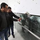 Trabajadores del Museo del Bardo señalan los impactos de bala en un cristal.