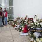 Unos visitantes guardan silencio ante las coronas de flores de distintos Gobiernos, en recuerdo de las víctimas.