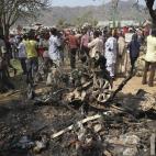 In a Sunday, Dec. 25, 2011 file photo, onlookers gather around a car destroyed in a blast next to St. Theresa Catholic Church in Madalla, Nigeria after an explosion ripped through a Catholic church during Christmas Mass near Nigeria's capital Su...