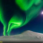 La aurora boreal comparte el cielo con una brillante luna en Islandia. Llamada así por Aurora, la diosa romana del amanecer, los haces de luz son el resultante de la colisión entre partículas en la atmósfera terrestre.