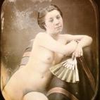 Una mujer desnuda con un abanico sentada en un sillón. Daguerrotipo estereoscópico coloreado a mano. 1850.