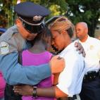 Los agentes de policía Greg Casem y Dominica Fuller consuelan a una niña en una vigilia en honor de Jamyla Bolden en Ferguson, Missouri (Estados Unidos), que murió en la cama el 19 de agosto después de que alguien disparara numerosas veces c...