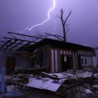Un rayo cruza el cielo sobre una casa en ruinas tras el paso de un tornado por Jefferson County, Alabama. El estado se encuentra asolado por desastres naturales, pues violentas inundaciones se combinan con el paso de los tornados.