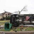 Una bandera de EEUU cuelga de un autobús volcado por un tornado en Rowlett, Texas.