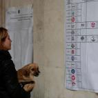 Una mujer observa en un colegio electoral en Roma un panel explicativo.