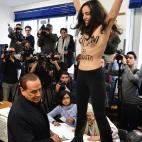 Momento en el que la activista de Femen se ha subido a la urna en la que Silvio Berlusconi, l&iacute;der de Forza Italia, se dispon&iacute;a a depositar su voto.