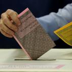 Un hombre mete su voto en la urna. Las papeletas rosas son para elegir a los miembros del Senado y las amarillas para elegir a los diputados del Parlamento.