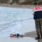 Un agente turco rescata en la orilla el cuerpo sin vida de un menor ahogado. La imagen más cruda de la tragedia.