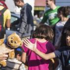 Una trabajadora de la iniciativa 'Ayuda a los Refugiados en Múnich' entrega un oso de peluche a un niño que espera con su familia un medio de transporte para acudir a uno de los centros de refugiados en la estación de Múnich (Alemania).
