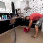 Un hombre recoje agua con un cubo en la cocina de su vivienda del barrio de las casas baratas de Blanca, Murcia.