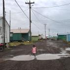 Una niña juega, solitaria, en los charcos del poblado. No es la India, no