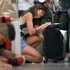 A passenger affected by the Ryanair strike fills out a claim form at the Terminal 2 of El Prat airport in Barcelona on June 30, 2022. - Around thirty Ryanair flights departing from and arriving in Spain were canceled, and 124 others were delayed...