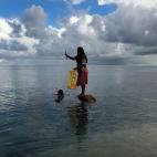 Binata Pinata sostiene subida sobre una roca un pez que ha pescado su marido Kaibakia , en la isla de Bikeman (en el Pacífico), en el lago de South Tarawa, el 25 de mayo.