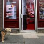 Un hombre camina con su perro por delante de una tienda vacía en Belcoo (Irlanda del Norte) el 3 de junios de 2013. En el exterior del local han colgado carteles con fotografías del interior de una carnicería. Los consejos locales de Irlanda ...