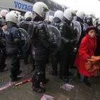 Una mujer camina entre los policías antidisturbios durante los enfrentamientos con los trabajadores de las plantas de acero de Arcelor Mittal en Lieja, 29 de enero de 2013. Arcelor Mittal, el mayor productor de acero del mundo, espera cerrar un...