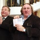 La estrella del cine francés Gerard Depardieu muestra su pasaporte sellado con un permiso de residencia, mientras que Vladimir Volkov, director de la República de Mordovia, aplaude. Todo esto durante una visita a la ciudad de Saransk, al sudes...