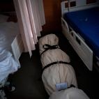 Una persona duerme en una cama a unos pocos pasos de un cad&aacute;ver, envuelto en bolsas protectoras y tendido en el piso de un centro de mayores, en Barcelona, el 19 de noviembre de 2020.