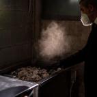 Un empleado del crematorio recoge las cenizas de un fallecido por covid en el tatatorio de M&eacute;mora, Girona.