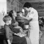 Una enfermera de la Cruz Roja estadounidense examina a una mujer y sus hijos víctimas de unas inundaciones en Tennessee (EE UU) en febrero de 1937.