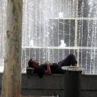 Un hombre descansa junto a una de las fuentes de la ciudad debido a las altas temperaturas que se registran en Córdoba.