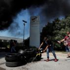 Los trabajadores de Nissan vierten combustible sobre neumáticos durante una protesta frente a la fábrica de Barcelona contra el posible cierre de la planta en la Zona Franca, en Barcelona.