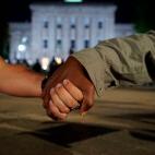 A white man and a black man clasp hands as police in the background guard the old state capitol in Raleigh, N.C., on Monday, June 1, 2020. It was the second day of protests in the North Carolina capital following the death of Minnesotan George F...