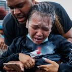 A protester reacts after being hit by pepper spray from police as their group of demonstrators are detained prior to arrest at a gas station on South Washington Street, Sunday, May 31, 2020, in Minneapolis. Protests continued sparked by the deat...
