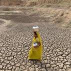 Una mujer india acarrea dos cántaros para recoger agua mientras cruza el fondo seco de una charca cerca de Mehmadpur. El estado de Gujarat se prepara para una fuerte sequía después de una temporada de monzón muy escasa.