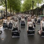 Femen activists hold placards shaped as tombstones, reading the name and the age of each women killed this year by their partner, during a protest action dedicated to the memory of the women killed by their partner or ex-partner and against the ...