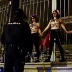 Spanish police officers arrive to drive out activists of women's rights organisation Femen who are chained to the gate of Palacio Vistalegre, with the words "against fascist vote" painted on their body, early on October 6, 2019 in Madrid, during...