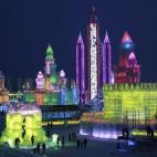 Los visitantes se acercan a las esculturas de hielo iluminadas para el festival internacional de figuras de nieve y hielo de Harbin (China).