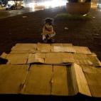 Ángela Cruz, de 5 años, prepara su cama de cartones en una calle de Manila (Filipinas).