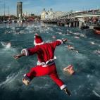Un participante vestido de Papá Noel salta al agua durante la Copa Nadal de Barcelona.
