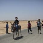 A Syrian refugee boy, followed by other children, enjoys riding a rented donkey pulled by his owner, during the Eid al-Fitr holiday that marks the end of the holy fasting month of Ramadan, at Zaatari refugee camp, near the Syrian border, in Mafr...