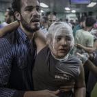 Un padre ayuda a su hijo herido en el ataque de Israel.
