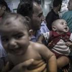 Varios hombres tratan de calmar a unos bebés aterrados y heridos tras el bombardeo israelí.