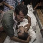 Un padre llora junto al cuerpo de su hijo, fallecido tras la ofensiva de Israel contra la escuela donde se refugiaban.