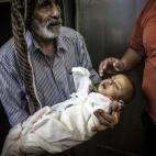 Un hombre palestino sostiene en sus brazos el cuerpo de un bebe de un año, fallecido por las heridas sufridas durante el bombardeo.