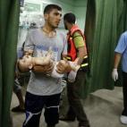 Un bebé palestino es evacuado en brazos tras el bombardeo.
