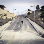 Una figura se aleja caminando en las calles asfaltadas de un proyecto de urbanización paralizado. Finestrat (Alacant)