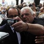 Hollande posa para un selfie con un hombre del público asistente al evento celebrado frente al ayuntamiento de Lieja.