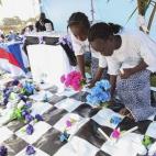 Niñas liberianas dejan flores en memoria de todas las víctimas del brote de ébola, durante un servicio religioso en Monrovia (Liberia). La Iglesia de Liberia cree que el ébola es un castigo divino por "actos inmorales como la homosexualidad".