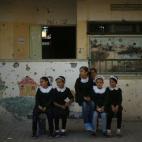 Estudiantes palestinas sonríen en su primer en la escuela, visiblemente dañada por los ataques israelíes.
