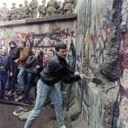 Un berlinés derriba parte del muro ante la indiferencia de los soldados.