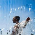 Un hombre combate el calor entre las aguas de la cascada de una cascada mientras juega con el agua en un parque de Washington DC.