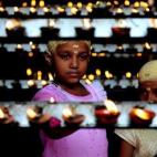 Dos devotos hindúes encienden velas durante la festividad de Aadi Kiruthigai en el templo de Chennai.