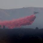 Un avión tira retardante de fuego en un incendio en Carmel Valley, California.