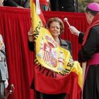 La alcaldesa de Valencia, Rita Barberá, observa a un sacerdote castrense mientras bendice la bandera española durante el día de la patrona de la Guardia Civil.