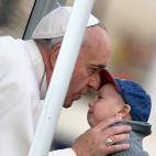 Antes de la tradicional misa matutina de los miércoles, el papa Francisco besó la frente de un niño en la plaza de San Pedro.